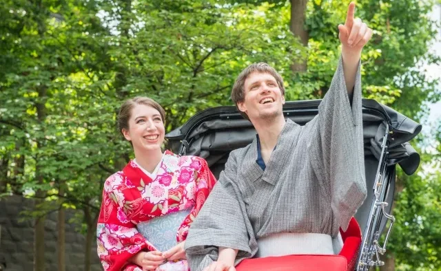 Seorang staf sedang membantu turis mengenakan kimono di sebuah toko sewa.
